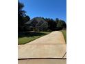 Long driveway leading to a well-maintained two-story home, enhanced by lush green surroundings at 704 Kenton Ct, Locust Grove, GA 30248