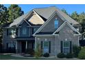 Charming two-story brick home with traditional design elements, including a covered porch and dark shutters at 704 Kenton Ct, Locust Grove, GA 30248
