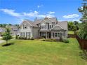 Eye-catching two-story home featuring lush green lawn with mature tree, with a gray exterior, and brick accents at 7820 Longview Dr, Cumming, GA 30041