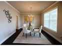 Elegant dining room features a glass table, chandelier lighting, and modern wall decor with great natural light at 3557 Bryant Meadows Cir, Buford, GA 30519