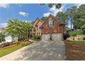 Brick home with a two-car garage and an expansive driveway, surrounded by mature trees at 809 Hillcrest Ln, Woodstock, GA 30189