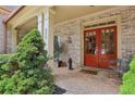 Inviting front porch with brick flooring, double red doors, and outdoor seating at 895 Mill Garden Pl, Cumming, GA 30040