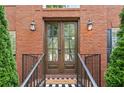 Close-up of a beautiful double-door entry with brick surround, stylish sconces and a 'welcome' mat at 530 Summerhill Dr, Roswell, GA 30075