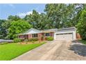 Brick home featuring a well-manicured lawn, mature trees and a two car garage at 3292 Ferncliff Ne Pl, Atlanta, GA 30324