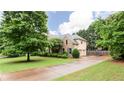 Traditional two-story home featuring a long driveway and landscaped front yard with mature shade trees at 4045 Hillcrest View Ct, Suwanee, GA 30024