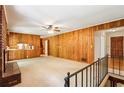Spacious living room featuring wood paneling, brick fireplace, carpet, and staircase at 415 Haven Ln, Marietta, GA 30066