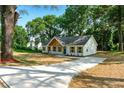 Inviting one-story home with new concrete driveway, board and batten siding, and mature trees at 124 Sims Dr, Hiram, GA 30141