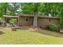 View of brick ranch home with a wooden pergola, stone fireplace, and a grassy yard at 3517 Greenway Dr, Marietta, GA 30008