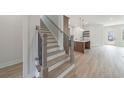 Hallway featuring stairs, an island, a light-filled living space, and wood-look flooring throughout at 160 South Village Ave, Holly Springs, GA 30115