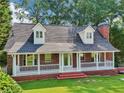 Beautiful brick home featuring a wide front porch, dormer windows, and lush green landscaping at 6841 Fairway Ridge Dr, Douglasville, GA 30134