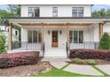 Inviting front porch with wood pillars, decorative shrubs, and a stained wood front door at 2602 Drew Valley Ne Rd, Brookhaven, GA 30319