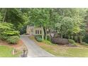 A charming home nestled among trees with a long driveway leading up to the house and an attached two car garage at 2722 Brookhaven Ln, Buford, GA 30518