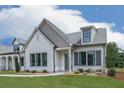 Charming single-Gathering home featuring a stone facade, manicured lawn, and black trimmed windows at 158 South Village Ave, Holly Springs, GA 30115