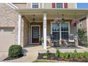 Inviting front porch with seating, hanging floral arrangements, black metal railings and manicured landscaping at 6298 Pierless Ave, Sugar Hill, GA 30518