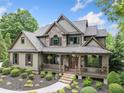 Beautiful home with stone and shake siding, covered porch, and manicured landscaping at 407 Maple Ridge Ct, Cumming, GA 30028