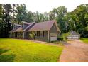 Exterior view featuring a two-car garage, stone accents, driveway, and large lawn area at 20 Lisa Ct, Stockbridge, GA 30281