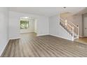 Spacious living room features grey wood flooring, neutral paint, staircase, and natural light at 310 Wolf Downs Way, Atlanta, GA 30349