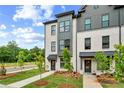 Modern townhome exterior featuring white brick, sleek black accents, and beautifully landscaped grounds at 449 Breccia Run, Mcdonough, GA 30253