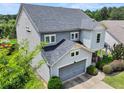An elevated side view of a two-story home with a two-car garage and welcoming front porch at 5730 Arbor Green Cir, Sugar Hill, GA 30518