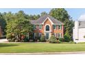 Charming brick two-story home with manicured lawn and mature trees showcasing classic curb appeal at 9310 Chapelwood Dr, Johns Creek, GA 30022