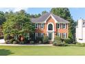 Charming brick two-story home with manicured lawn and mature trees showcasing classic curb appeal at 9310 Chapelwood Dr, Johns Creek, GA 30022