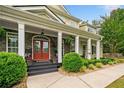 Inviting front porch with stone accents, classic columns, and a vibrant red front door at 360 Glade Knoll Trail Trl, Fayetteville, GA 30215