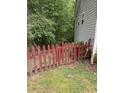 A quaint red picket fence accents the side yard of this home with light gray siding at 6305 Eidson Dr, Cumming, GA 30041