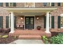 Close up of front porch with black metal door, stately white columns, and brickwork at 4246 N Mountain Ne Rd, Marietta, GA 30066