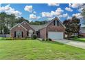 Charming brick home features a well-manicured lawn and attached two-car garage, set beneath a beautiful sky at 2790 Meadow Gate Way, Loganville, GA 30052