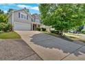 Wide driveway leading to a two-story home with lush greenery, inviting curb appeal, and attached garage at 207 Diamond Valley Pass, Canton, GA 30114