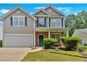 Charming two-story home with a well-maintained lawn, attached garage, and inviting blue door at 207 Diamond Valley Pass, Canton, GA 30114