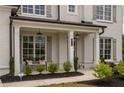 Inviting front porch with decorative columns, elegant lighting, and tasteful landscaping adds to the home's charm at 7345 Vale Ct, Cumming, GA 30028