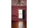 Pink bedroom featuring hardwood floors, a ceiling fan, and a window with blue curtains at 352 Price Rd, Carrollton, GA 30116