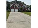 Two-story brick home with attached two-car garage featuring a long concrete driveway and mature landscaping at 3381 Walkers Ridge Rd, Dacula, GA 30019