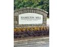 Stone entrance sign for Hamilton Mill, enhanced by landscaping with colorful plantings and flowers at 3381 Walkers Ridge Rd, Dacula, GA 30019