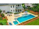An aerial view of a backyard featuring a sparkling pool, tanning deck, outdoor seating, and fire pit at 5963 Wild River Vw, Sugar Hill, GA 30518