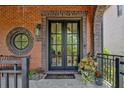 Welcoming front door with a round window, brick facade, and stylish planters on a stone porch at 210 4Th St, Fayetteville, GA 30214