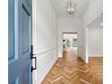 Light filled entryway with beautiful herringbone hardwood flooring and wainscoting at 5631 Queensborough Dr, Atlanta, GA 30338