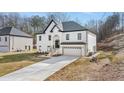 Side view of a two-story home with white brick, black trim, two-car garage, and long driveway at 4410 Ross Estates Ct, Snellville, GA 30039
