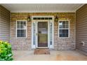 Close up of the front porch with stone facade and decorative windows on either side of the doorway at 99 Rainwater Ln, Dallas, GA 30157