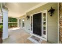 Welcoming front porch with neutral siding, charming lights, and a black front door with glass inserts at 1205 Compass Pointe Xing, Alpharetta, GA 30005