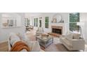 Sunlit living room with a cozy fireplace, hardwood flooring, and views of the outdoors from multiple windows at 112 Birchwood Pass, Canton, GA 30114