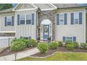 A beautifully landscaped home entrance features blue shutters, stone accents, and a charming flower garden at 79 Little Creek Manor Dr, Dallas, GA 30157