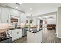 Well-lit kitchen with island that opens to living room with stone fireplace and dark brown sofa at 10300 Medridge Cir, Johns Creek, GA 30022