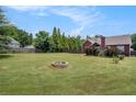 Sprawling backyard featuring a stone fire pit, lush green grass, and privacy fence with mature trees in the background at 1951 Chambers Rd, Mcdonough, GA 30253