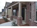 Inviting brick porch with classic columns and a dark-colored front door with black door hardware at 1530 Horseshoe Creek Ln, Cumming, GA 30041