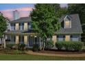 Charming two-story home featuring a covered porch, blue shutters, and lush greenery at 3970 Genoa Ct, Duluth, GA 30096