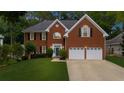 Beautiful brick home with a two-car garage, well-manicured lawn, mature trees, and landscaping at 10865 Misty Moon Ct, Alpharetta, GA 30022