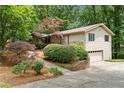 Exterior side view of home with attached garage, surrounded by lush greenery at 217 Millbrook Farm Rd, Marietta, GA 30068