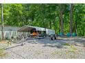 Gravel driveway next to a boat trailer and a carport with a jet ski with woods surrounding the home at 1000 Delta Dr, Canton, GA 30114